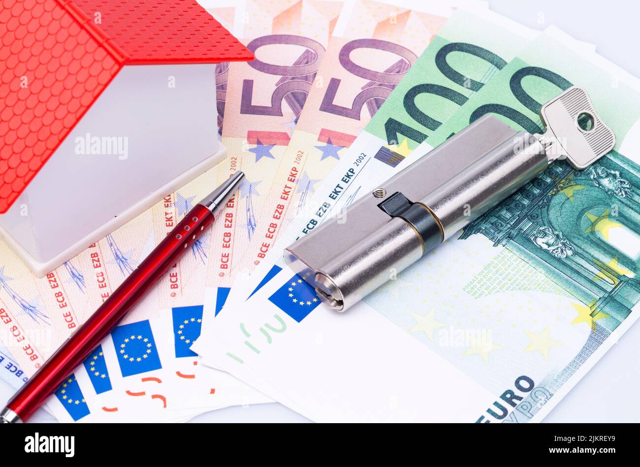 Concept image with model house, lock cylinder, ball pen and banknotes Stock Photo