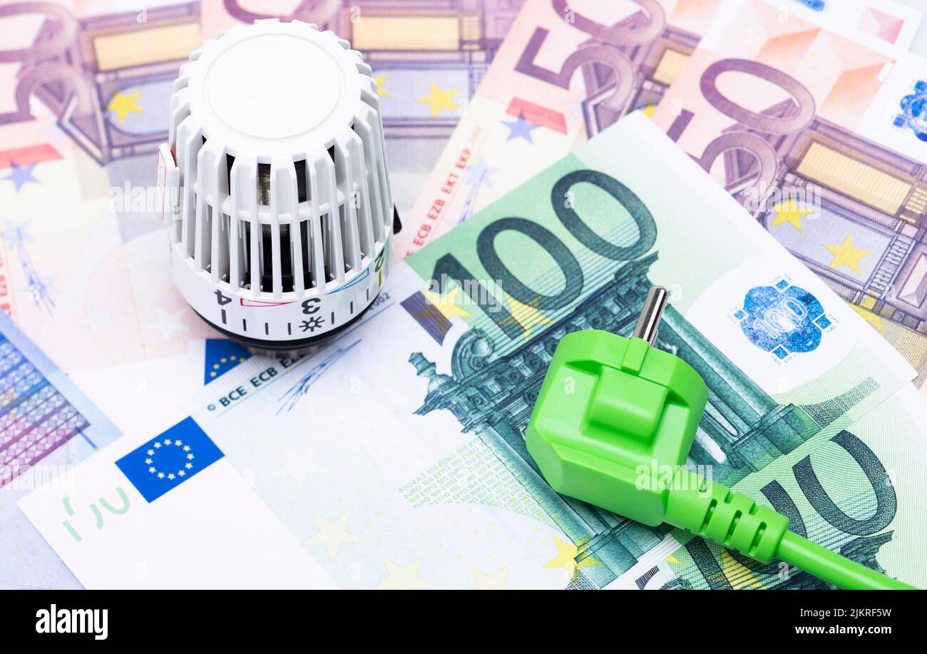 The photo shows a heating thermostat and a power cable beneath banknotes Stock Photo