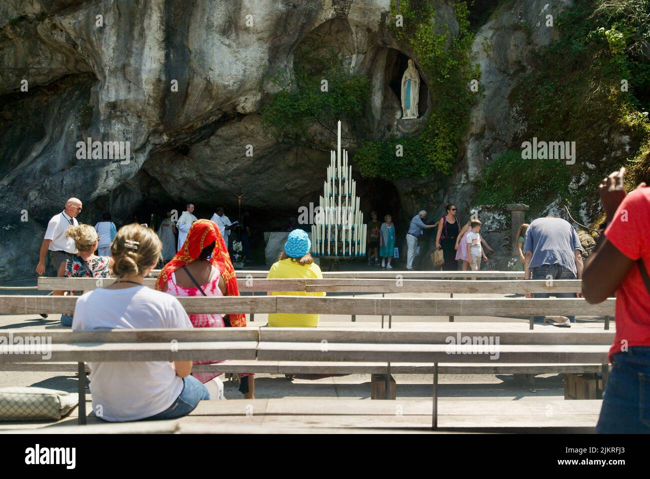 People gathered at the Grotto of Massabielle/Grotto of the Apparitions at Sanctuary of Our Lady of Lourdes, Pilgrimage at Lourdes people in the grotto Stock Photo