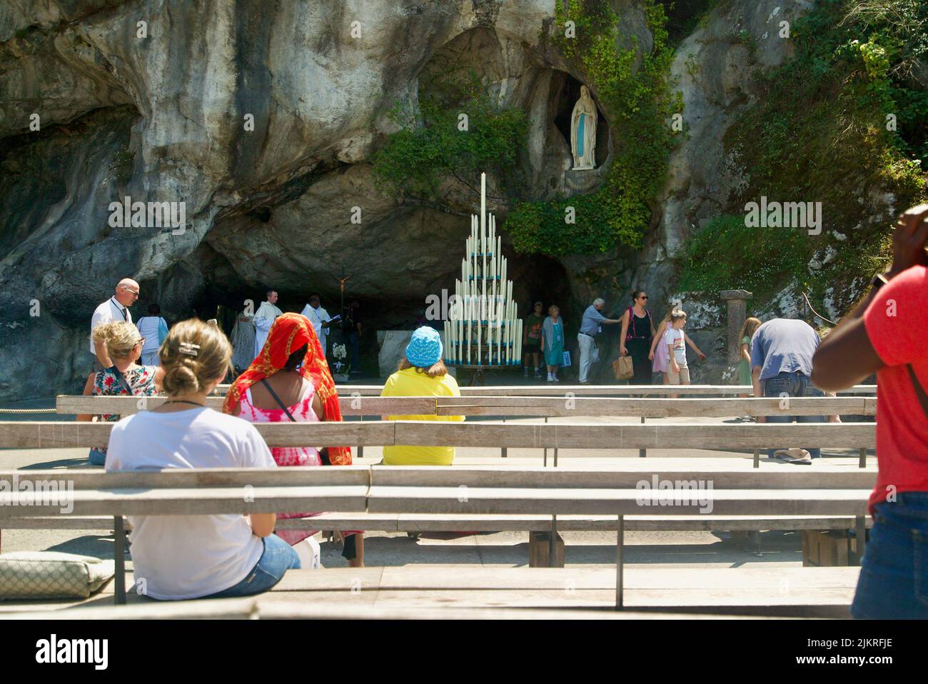 People gathered at the Grotto of Massabielle/Grotto of the Apparitions at Sanctuary of Our Lady of Lourdes, Pilgrimage at Lourdes people in the grotto Stock Photo