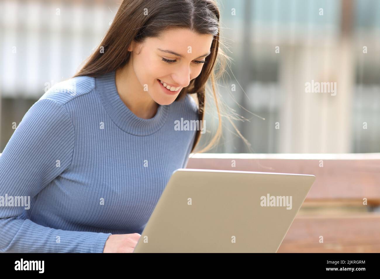 Happy teen using laptop sitting in a park Stock Photo