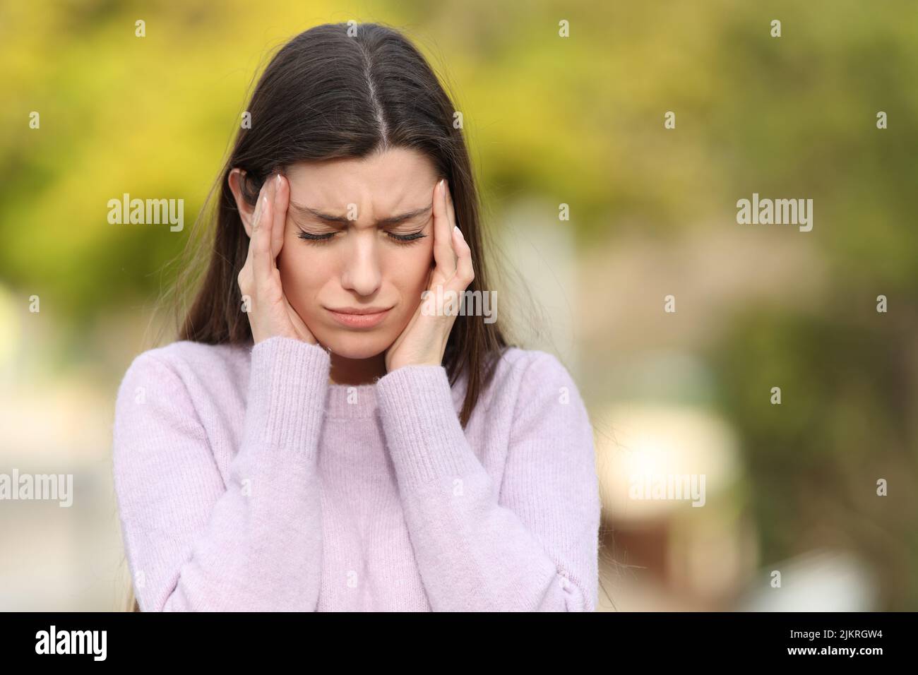 Front view portrait of a teen stressed suffering migraine in a park Stock Photo