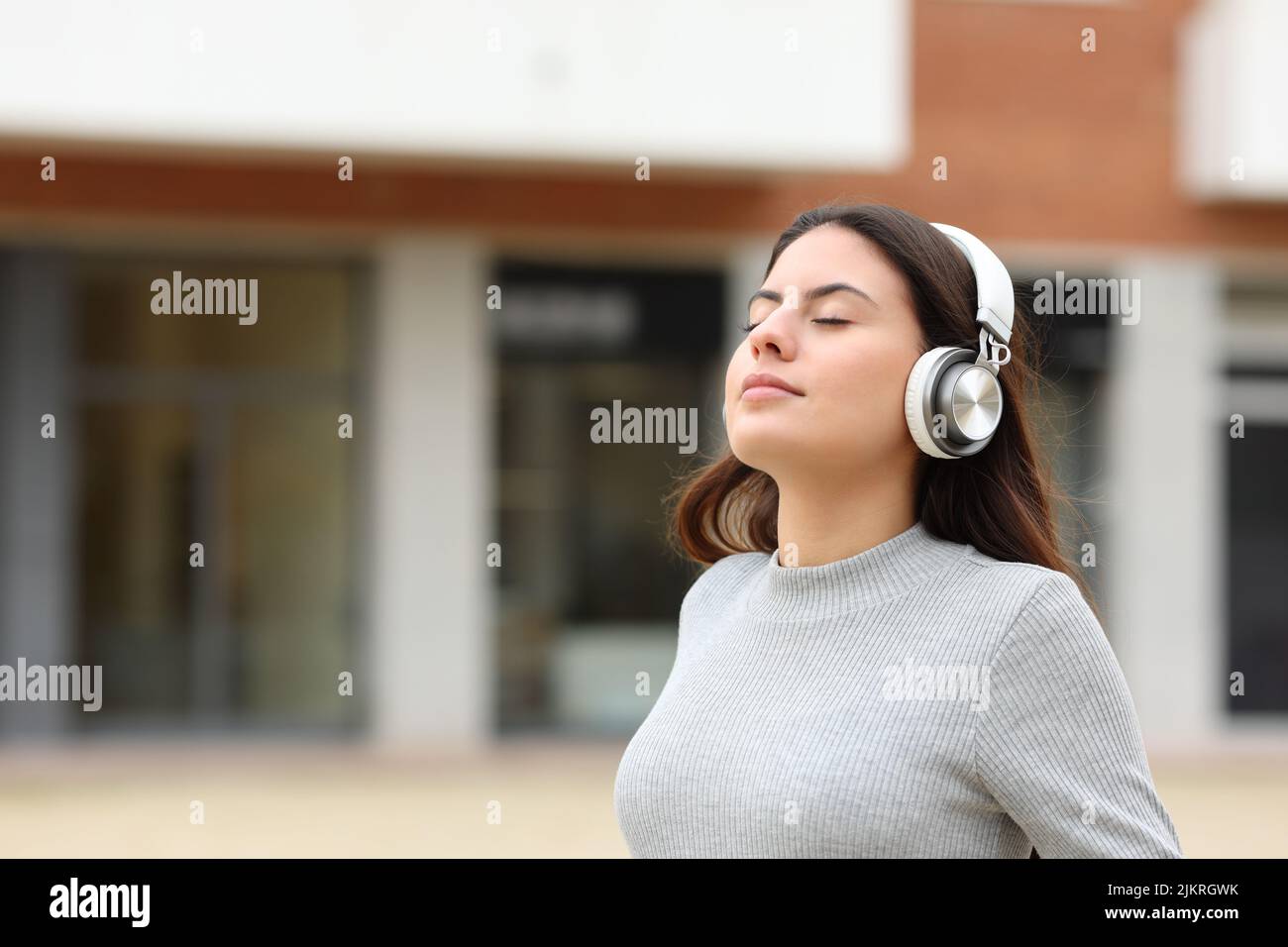 Teen meditating with wireless headphones in the street Stock Photo