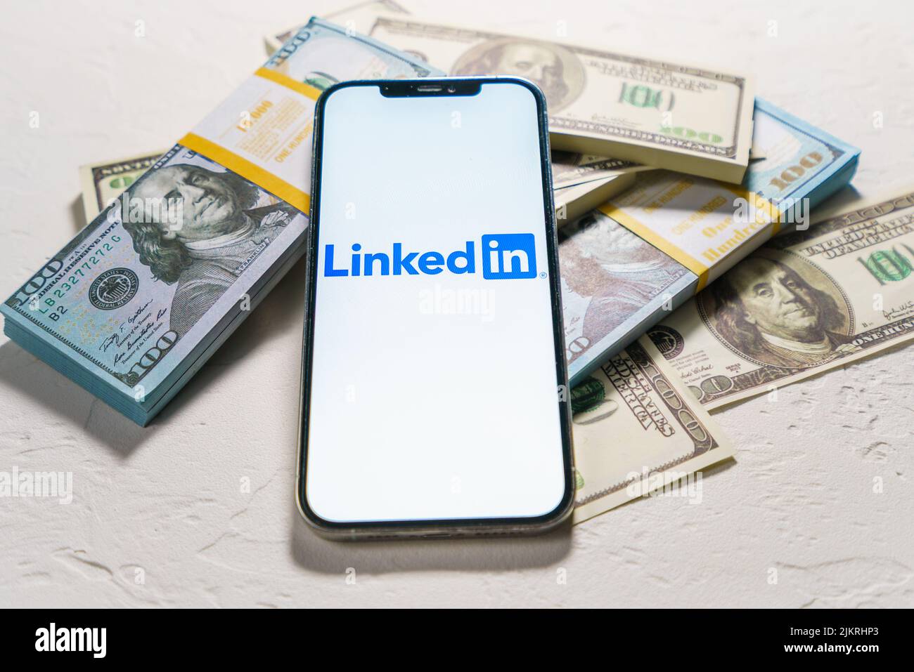 Berlin, Germany - February 02, 2022:  LinkedIn logo on Apple iPhone 12 Pro Max. Application for searching new job, dollar money on the background Stock Photo