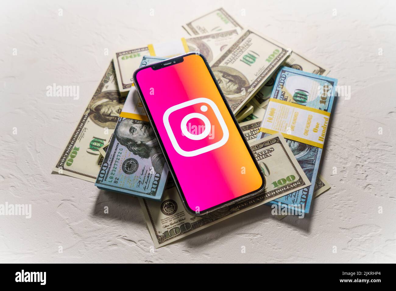 Berlin, Germany - February 02, 2022: Money and smartphone displaying the Instagram logo. Social media. Instagram is a photo-sharing app for smartphone Stock Photo