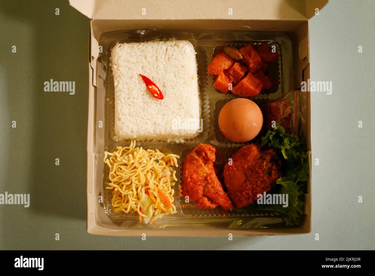 Rice Box or Indonesian lunch box with chicken meat, tofu, spicy potato, noddle, egg and vegetable Stock Photo