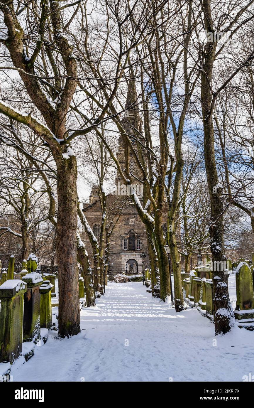 Parish Church of St Cuthbert viewed through tree lined footpath with a carpet of snow in city centre of Edinburgh in Scotland, UK Stock Photo