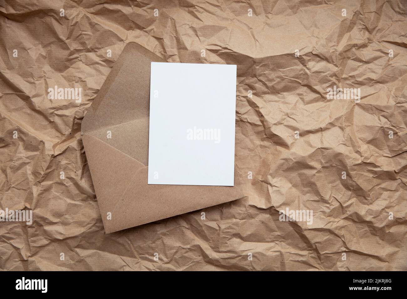 Blank card with kraft brown paper envelope template mock up on crumpled brown paper Stock Photo