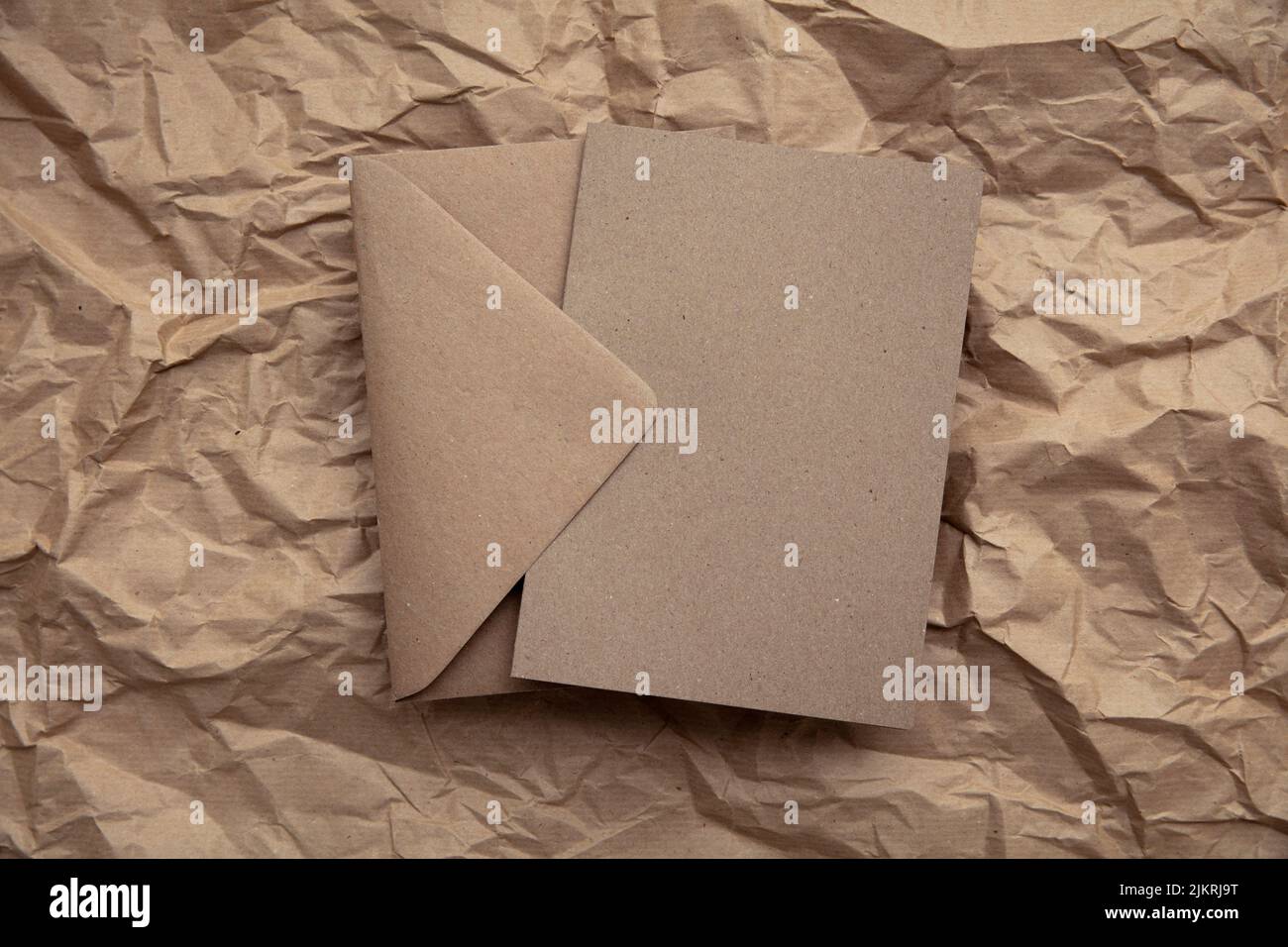 Blank card with kraft brown paper envelope template mock up on crumpled brown paper Stock Photo