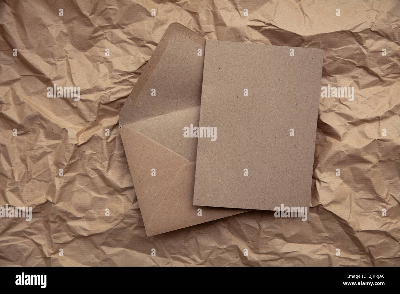 Blank card with kraft brown paper envelope template mock up on crumpled brown paper Stock Photo