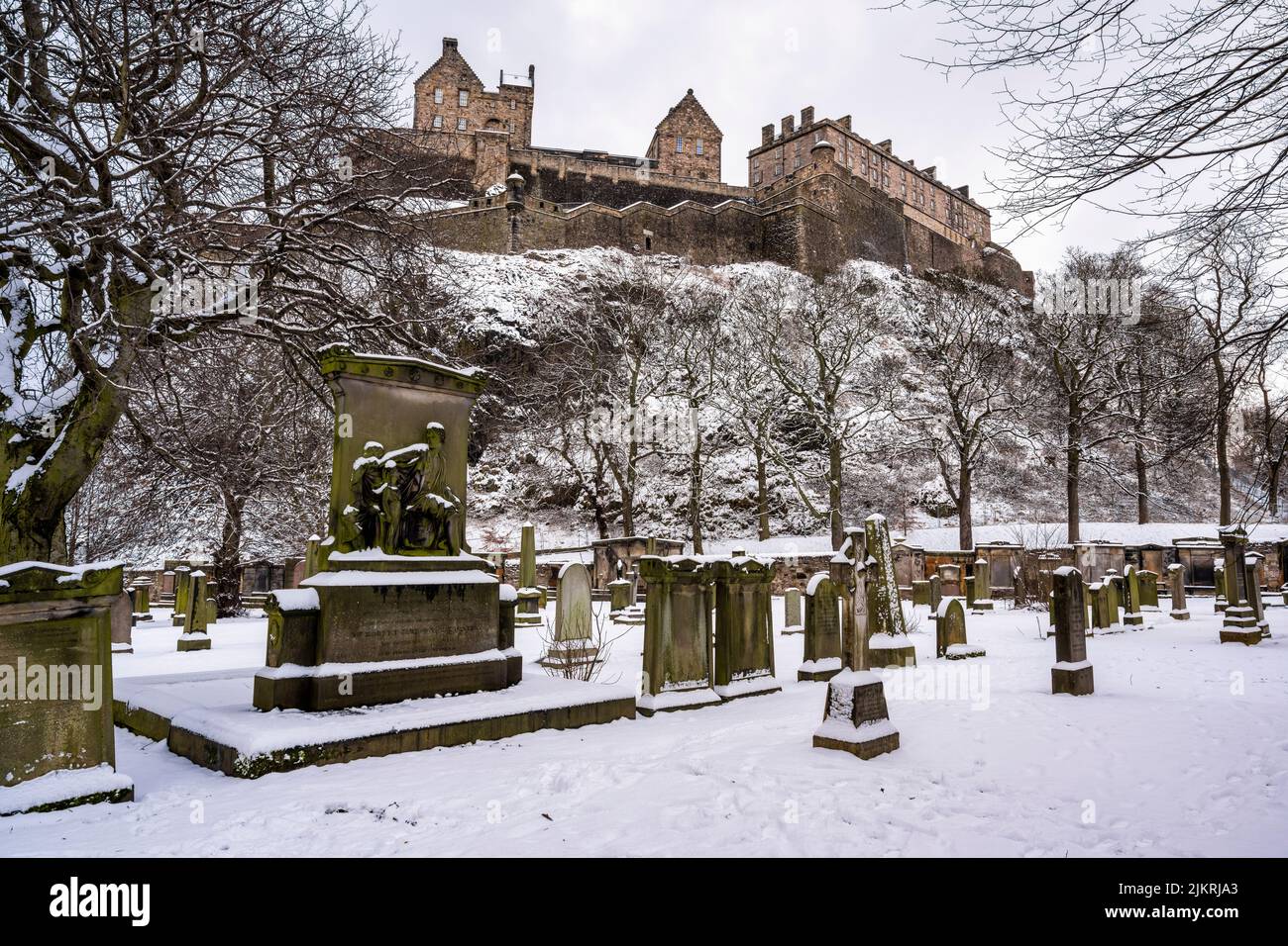Gravestones in St Cuthbert's Graveyard with a carpet of snow, with Edinburgh Castle in background, in city centre of Edinburgh in Scotland, UK Stock Photo