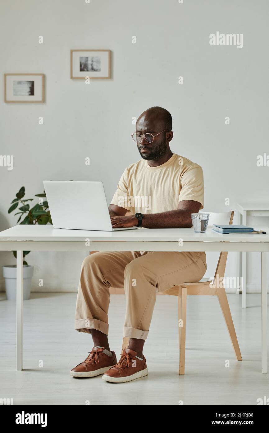 African young businessman sitting at his workplace at office and using laptop for online work Stock Photo