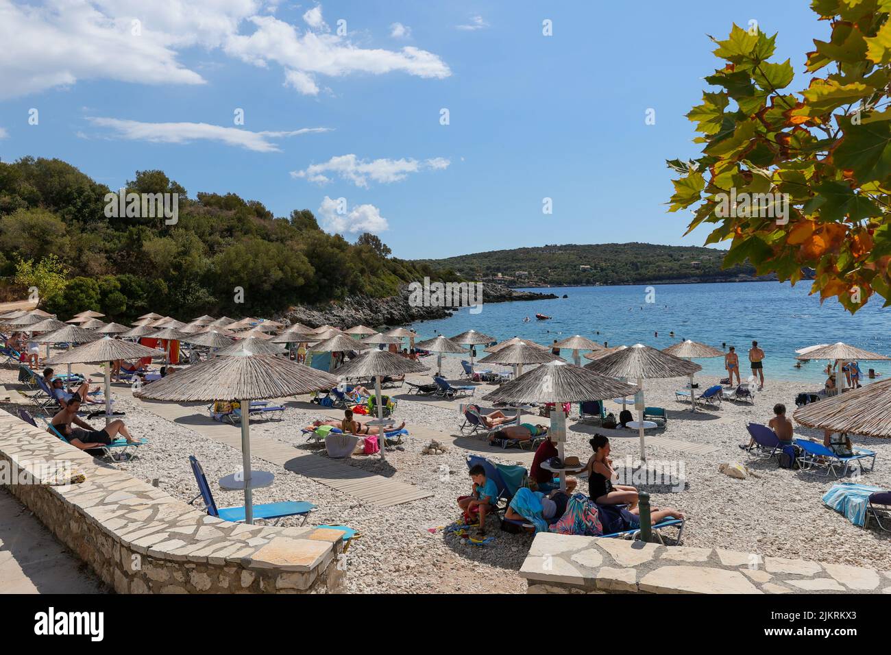 Tourists relaxing on sunloungers on the idillic Ammoussa Beach on Lefkada island, Greece. A perfect Greek summer destination. Stock Photo