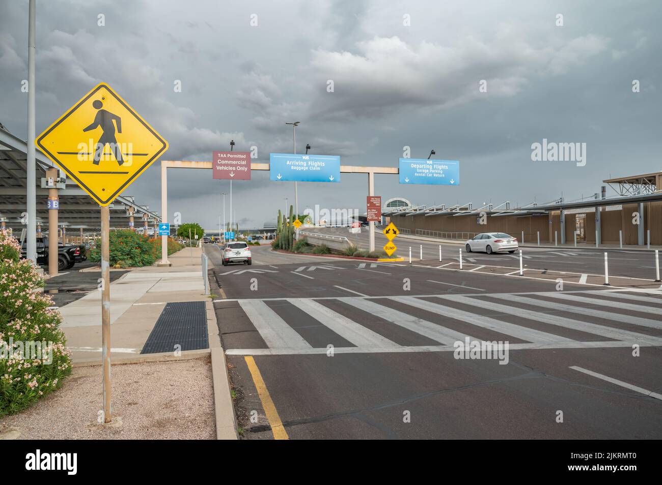 Vehicles arrive at Tucson International Airport next to parking lot. Directional signs display. Stock Photo