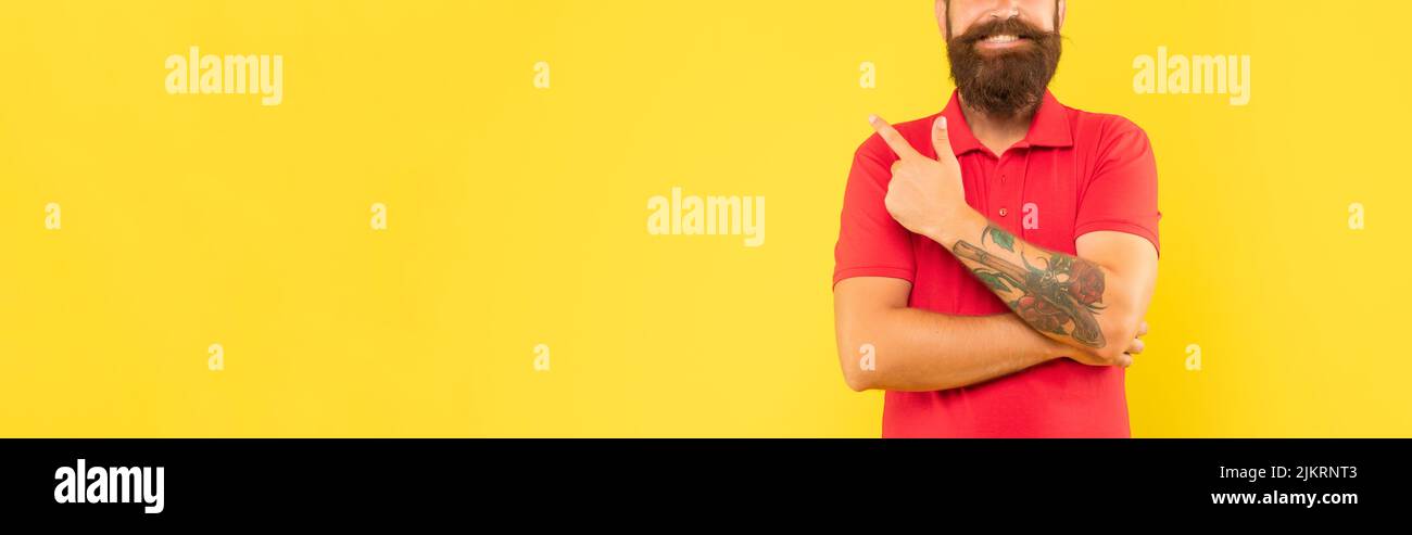 Happy bearded man crop view in casual red tshirt pointing finger aside copy space, advertise Stock Photo