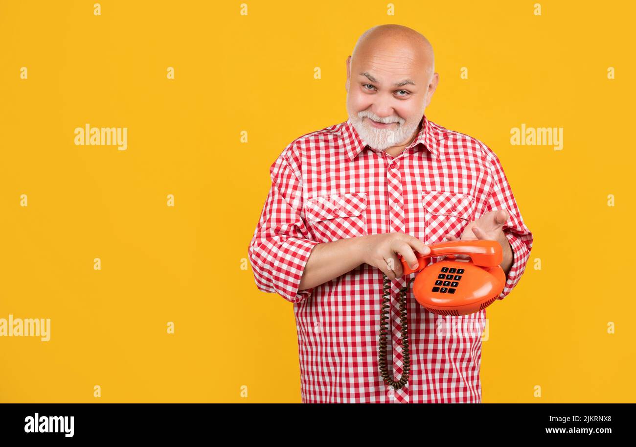 positive aged man with retro telephone on yellow background Stock Photo