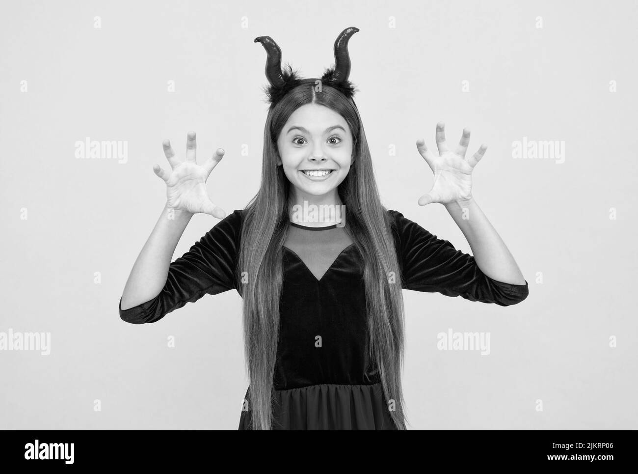 I will eat you. child in imp horns on yellow background. kid wear devil horns show claws. childhood autumn holiday. funny teen girl ready to celebrate Stock Photo