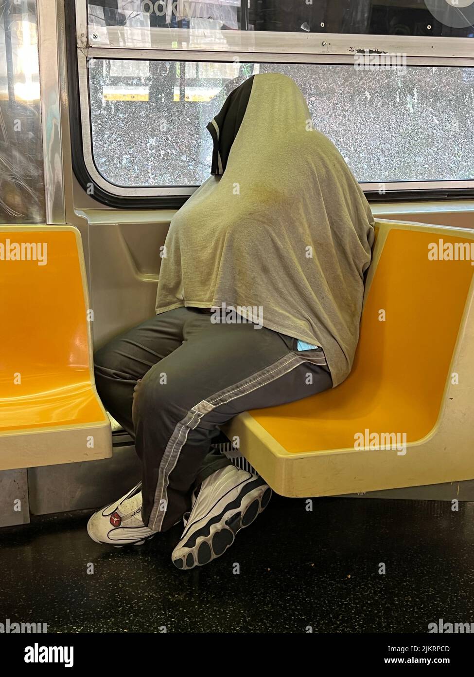 Homeless man retreated into his own world riding a New York City subway train in Brooklyn. Stock Photo