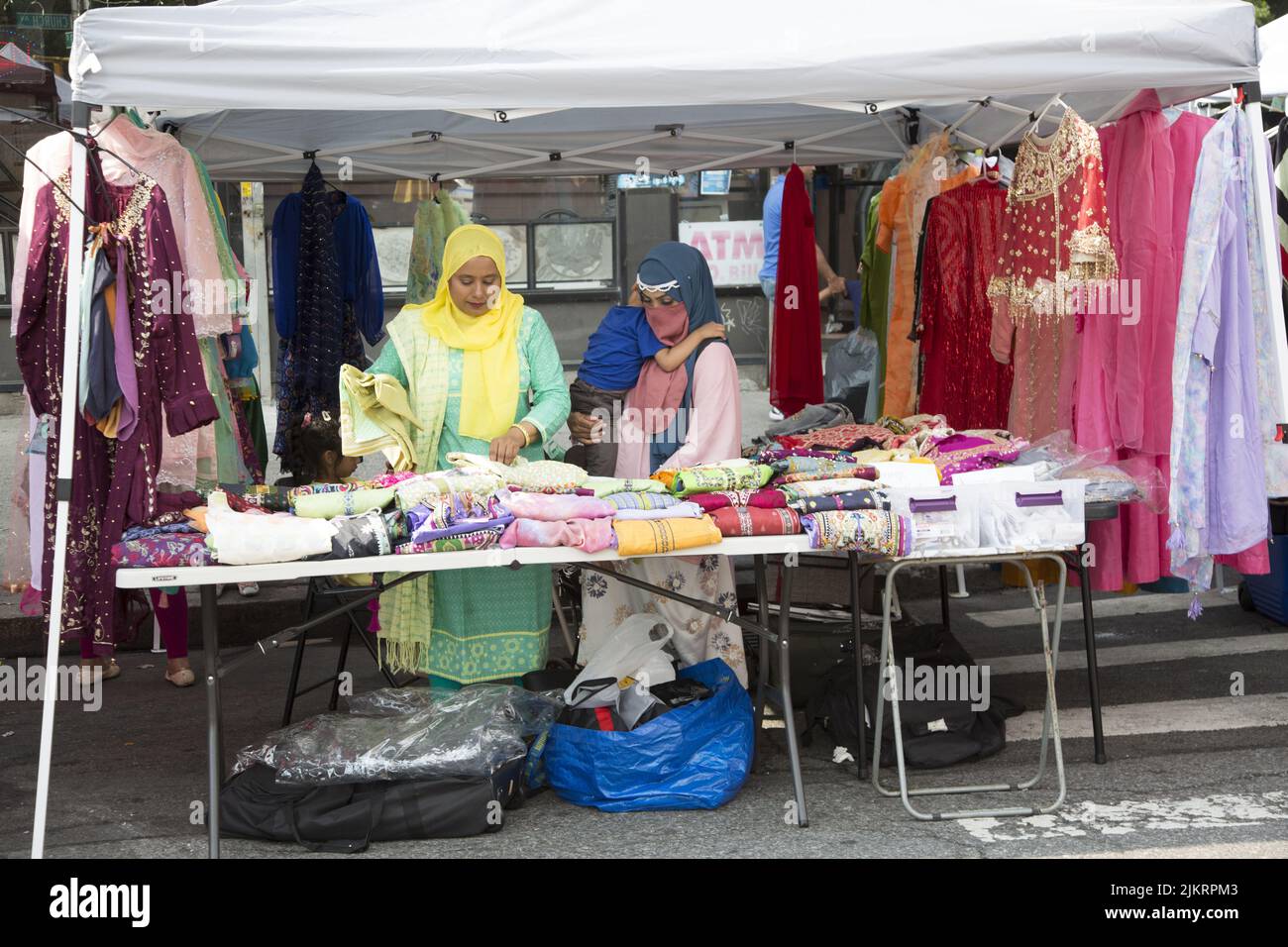 Women sell colorful dresses and material at a Bangladeshi Street Fair on Church Avenue in the Kensington neighborhood of Brooklyn, New York. Stock Photo