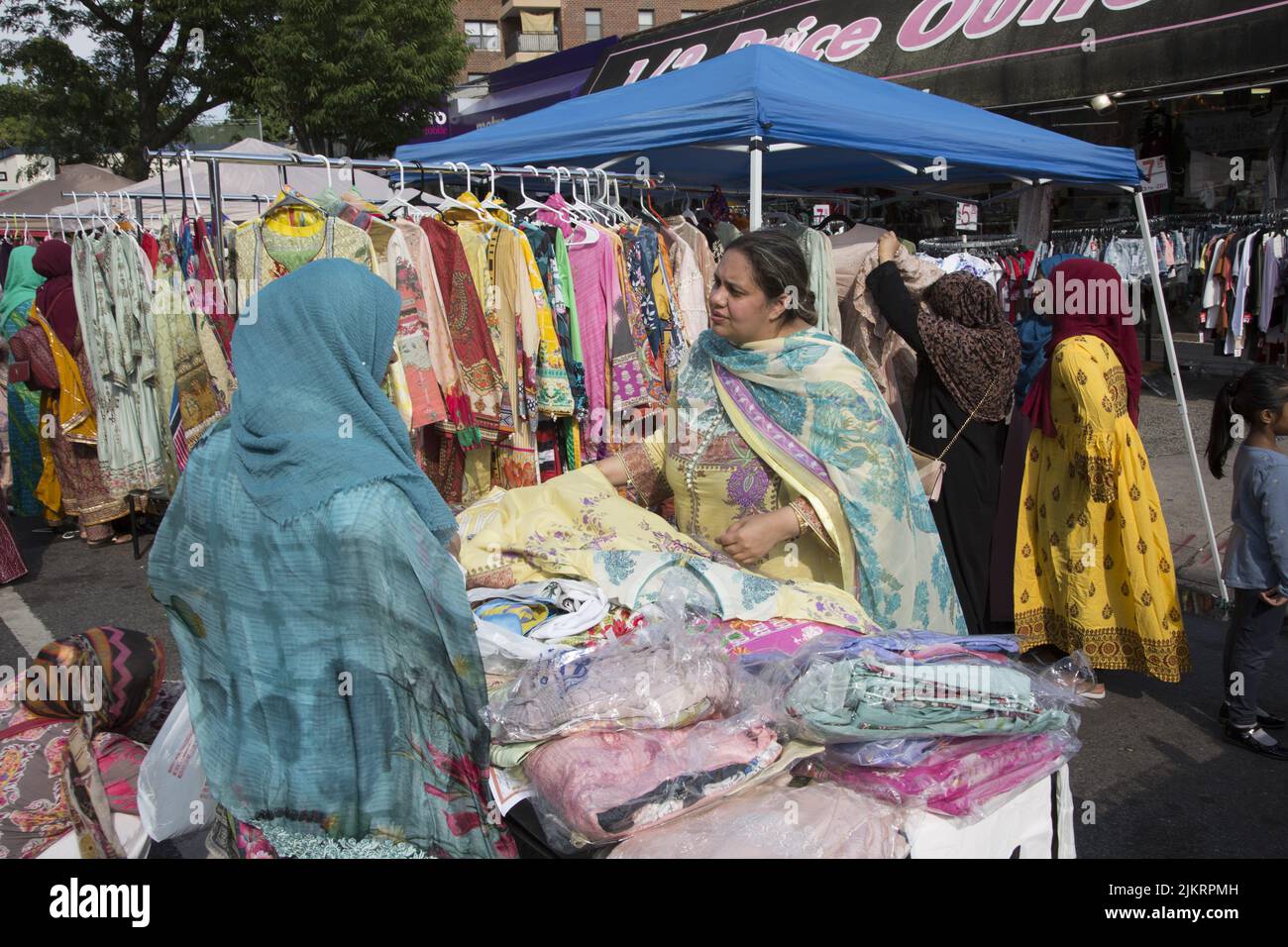 Woman sells colorful dresses and material at a Bangladeshi Street Fair on Church Avenue in the Kensington neighborhood of Brooklyn, New York. Stock Photo