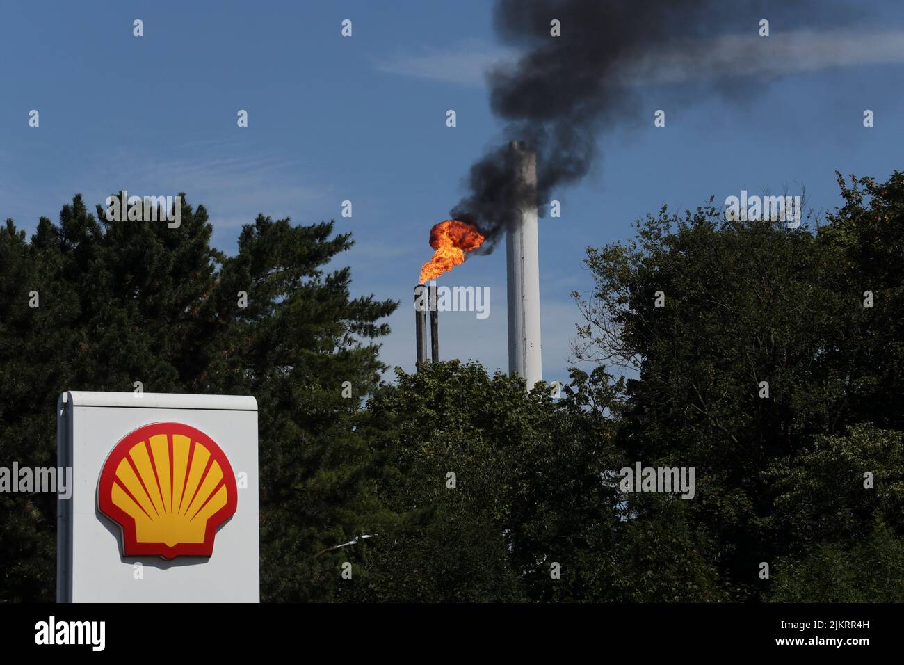 The sign of a Shell petrol station is seen in front of a burning pilot flame atop a flare stack at the refinery of the Shell Energy and Chemicals Park Rheinland in Godorf near Cologne, Germany, August 3, 2022.  REUTERS/Wolfgang Rattay Stock Photo