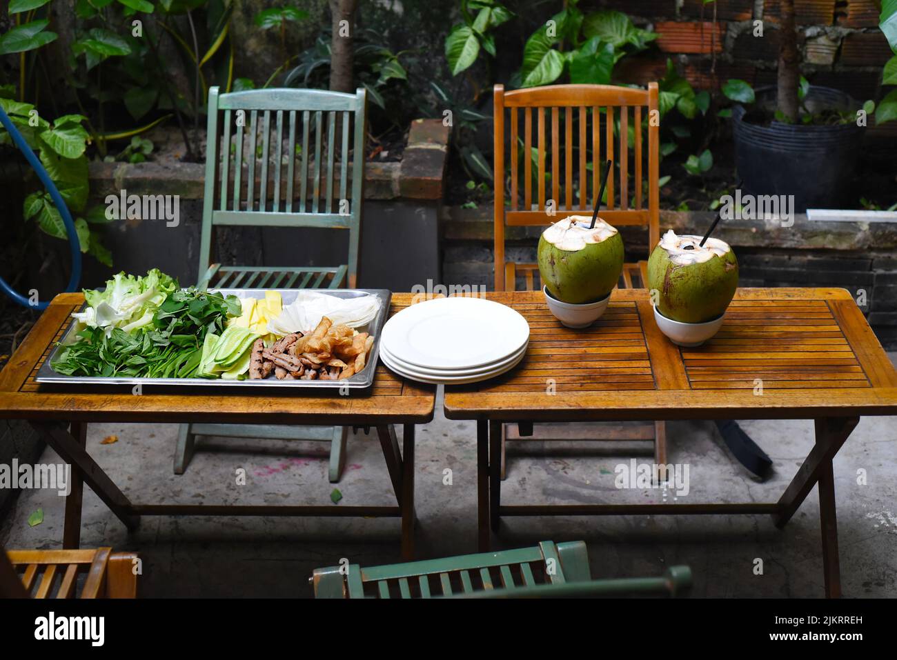 Traditional Vietnamese meal greens roasted meat with rice paper and coconut drinks on wooden table Stock Photo