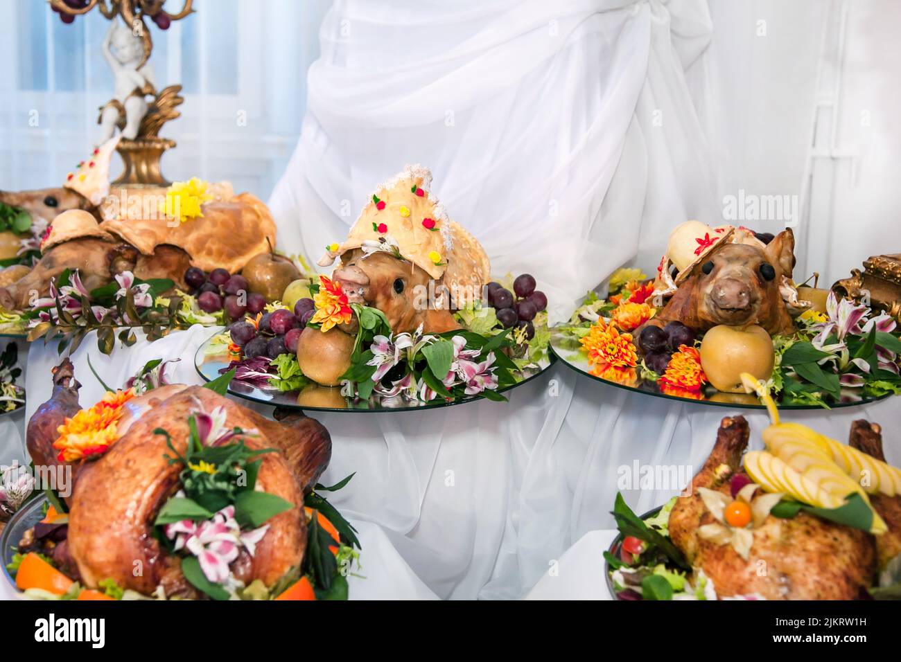 Buffet table with meat snacks, baked pigs in dough, cheese, turkey with