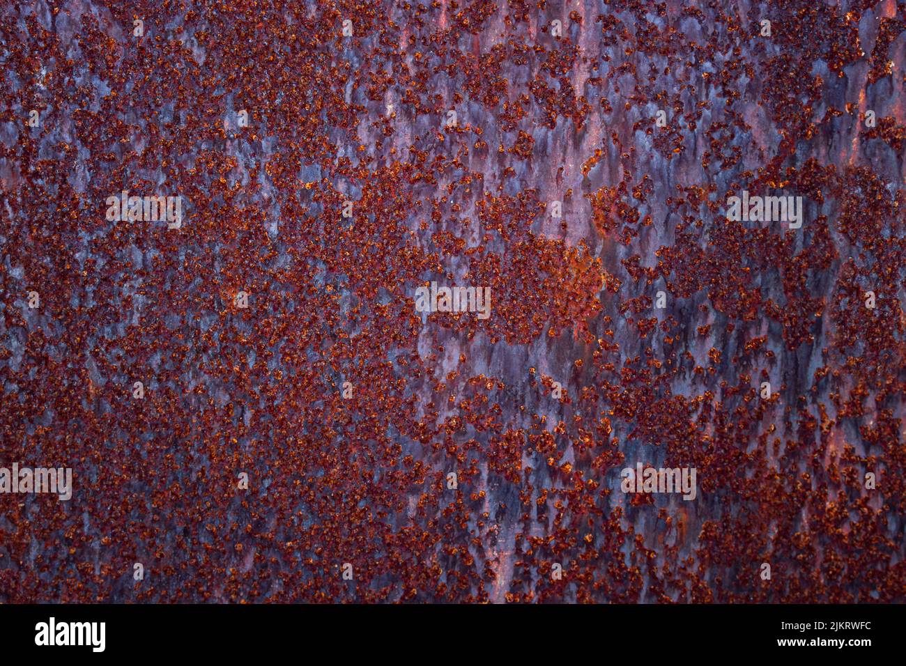 Corroded rusty metal texture with cracked red paint residues. Abstract background with empty space for text Stock Photo