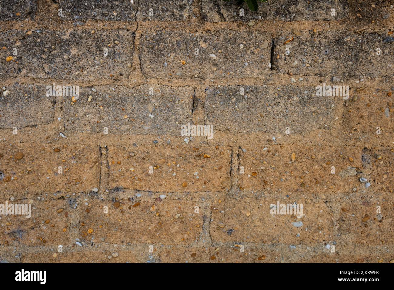 Clay wall background. Detail of old wall with roughly built bricks pattern and mixed pebbles. Texture of rough rustic wall with copy space Stock Photo