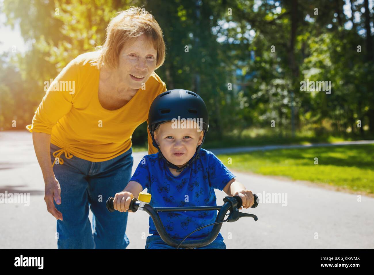 grandmother teaching his grandson to ride a bicycle. child learning to ride a bike Stock Photo