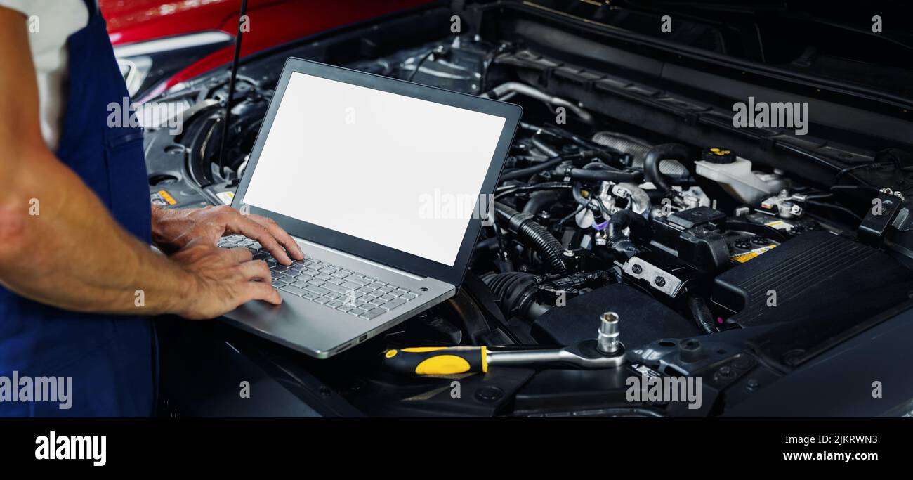 engine diagnostics - car mechanic using laptop computer to diagnose vehicle motor in repair shop. blank screen copy space Stock Photo