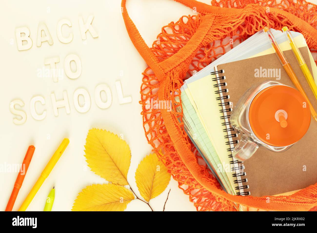 Card of Back to school. Eco friendly, School sale concept. School supplies in a bright yellow textile bag on a light background with autumn leaves and Stock Photo