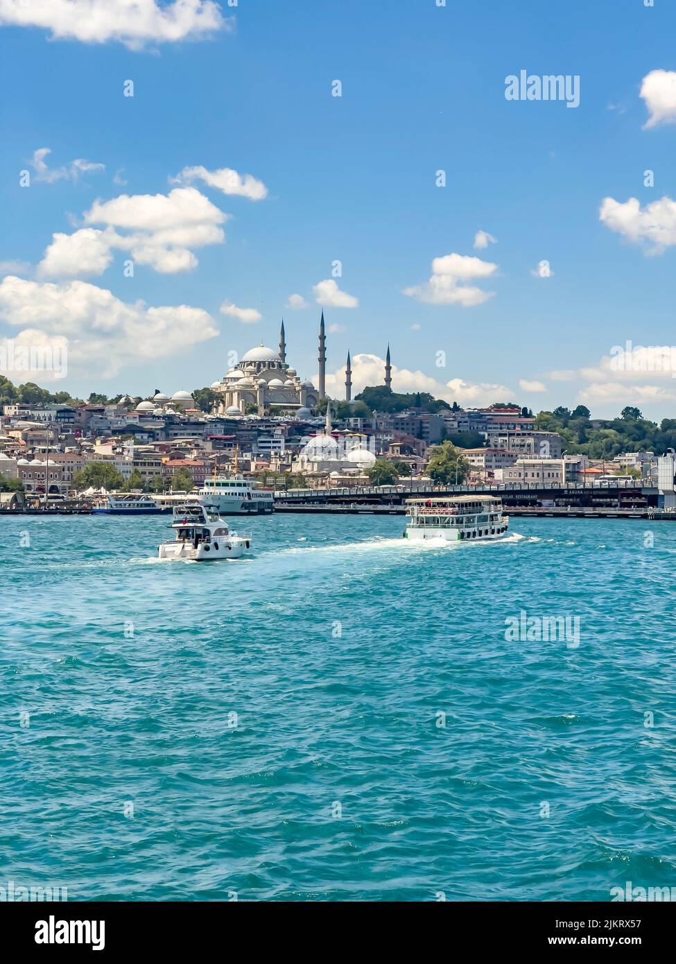Ferries moving towards Eminonu station in Istanbul on a sunny day with Yeni Cami (New Mosque) in background. Beautiful travel destination postcard Stock Photo