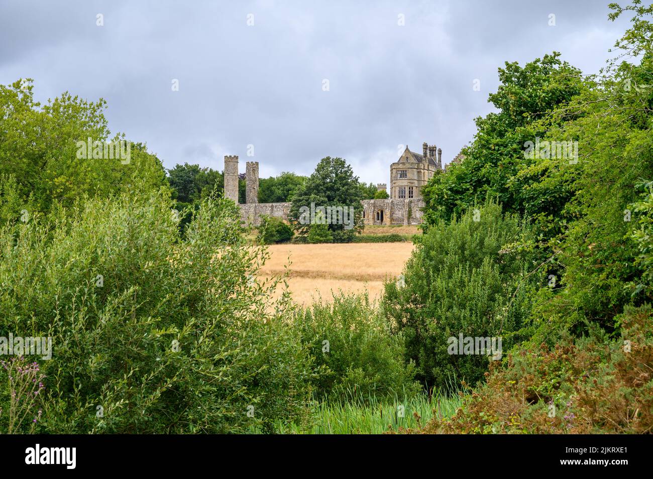 Battle Abbey situated on top of the battlefield of the Battle of Hastings in 1066 with trees and bushes in the foreground, East Sussex, England. Stock Photo