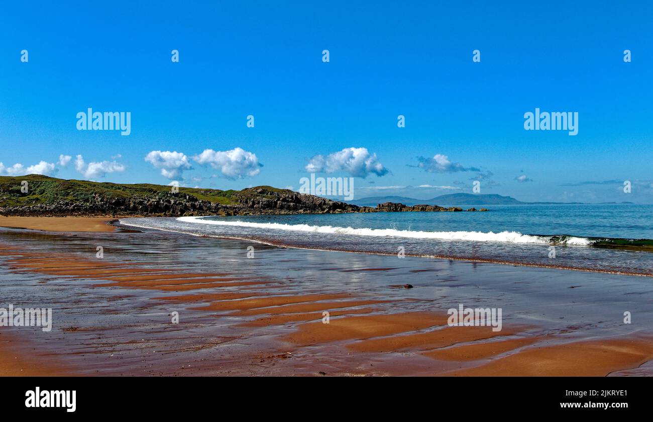 RED POINT BEACH ROSS AND CROMARTY SCOTLAND BLUE SEA AND SKY AND RED SAND WASHED BY WAVES Stock Photo