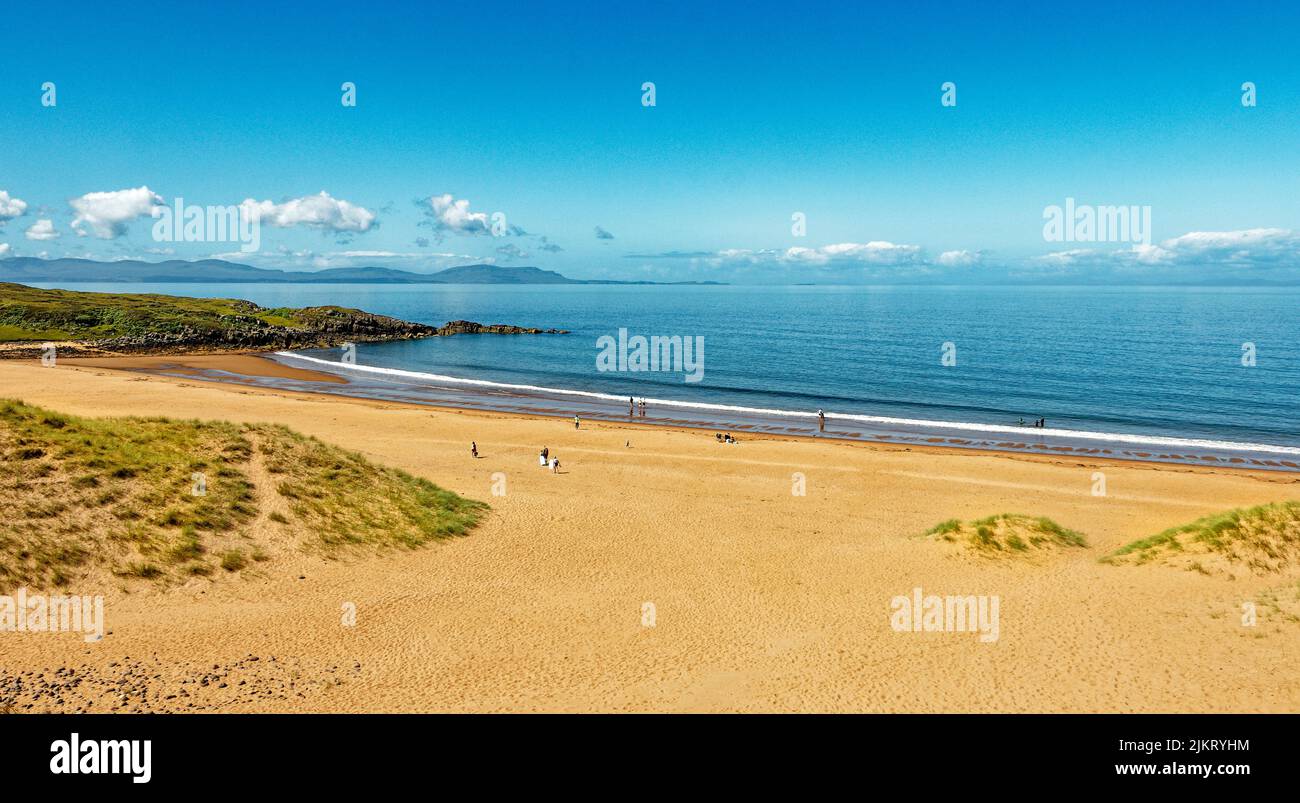 RED POINT BEACH ROSS AND CROMARTY SCOTLAND BLUE SEA AND SKY WITH PEOPLE ON THE RED SANDS Stock Photo