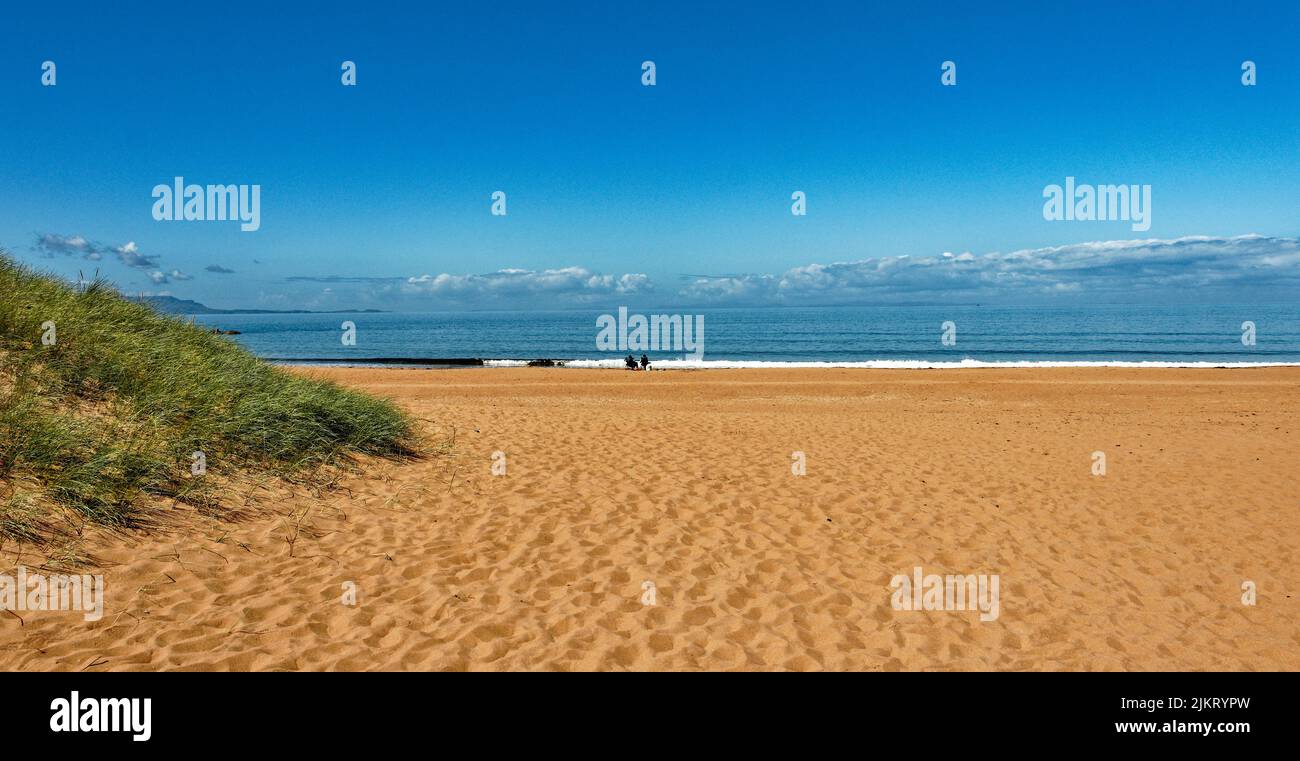 RED POINT BEACH ROSS AND CROMARTY SCOTLAND RED SAND BLUE SEA AND SKY AND A GRASS COVERED DUNE Stock Photo