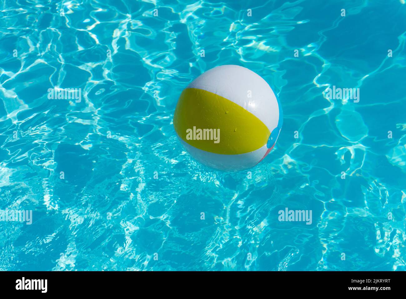 Inflatable beach ball floating on a summer swimming pool Stock Photo