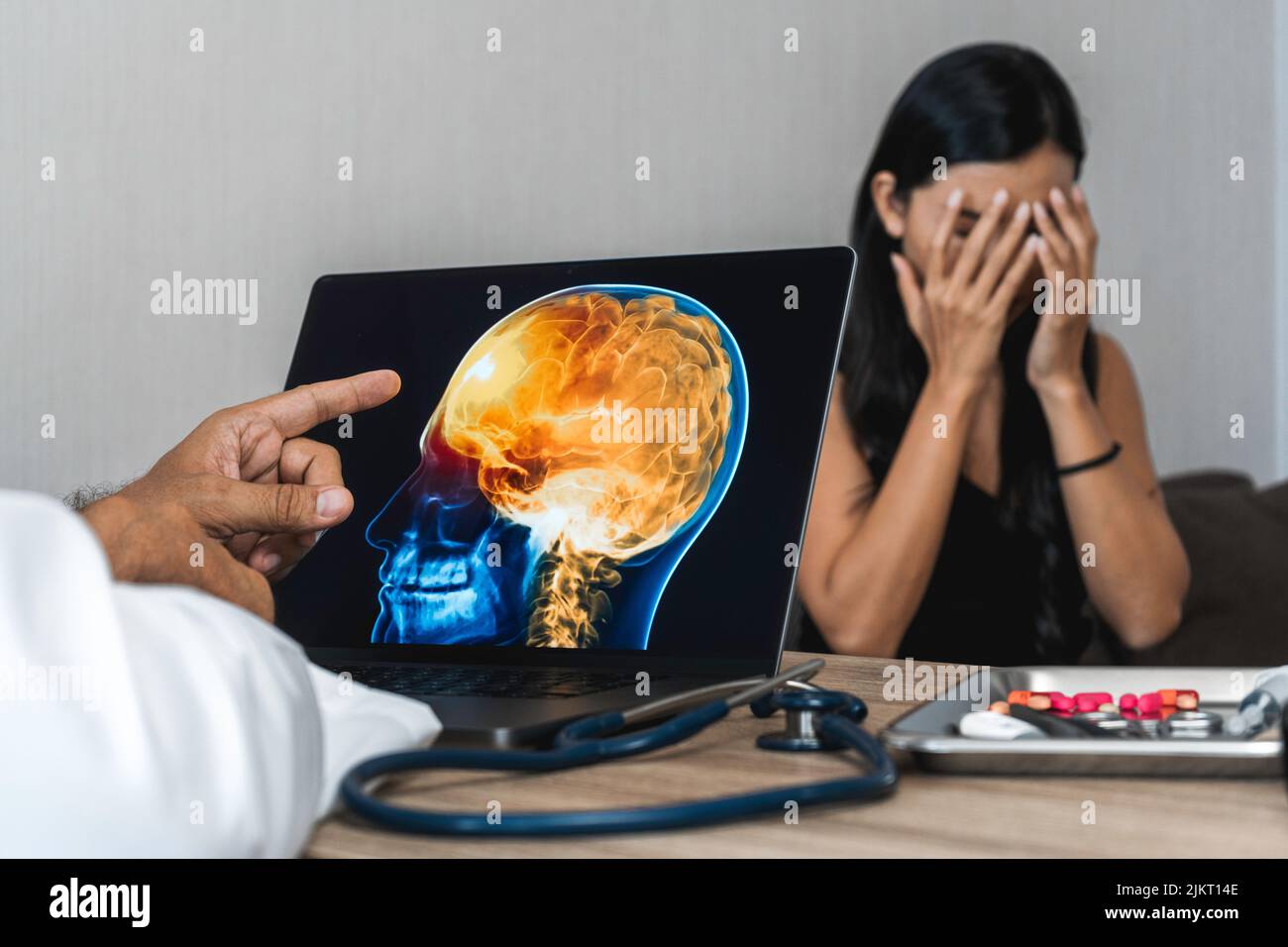 Doctor showing a x-ray of pain in the brain on a laptop. Migraine Headache Stock Photo