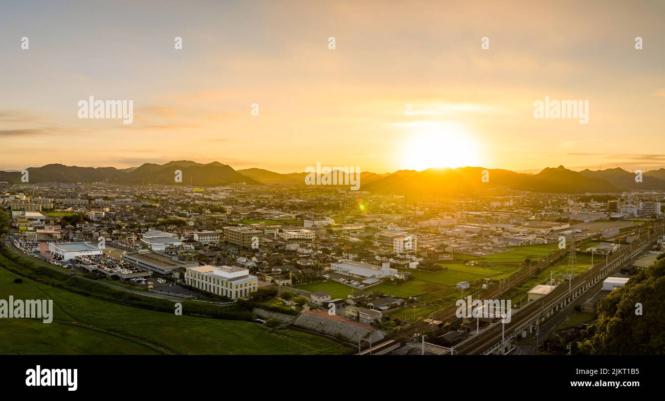Bright sunrise over small town and railroad tracks with distant mountains Stock Photo