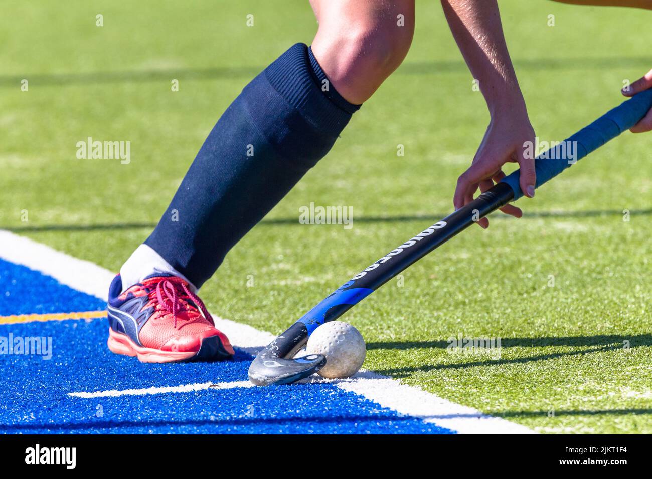 Hockey game female player hand leg short corner with ball and stick on astro turf Stock Photo