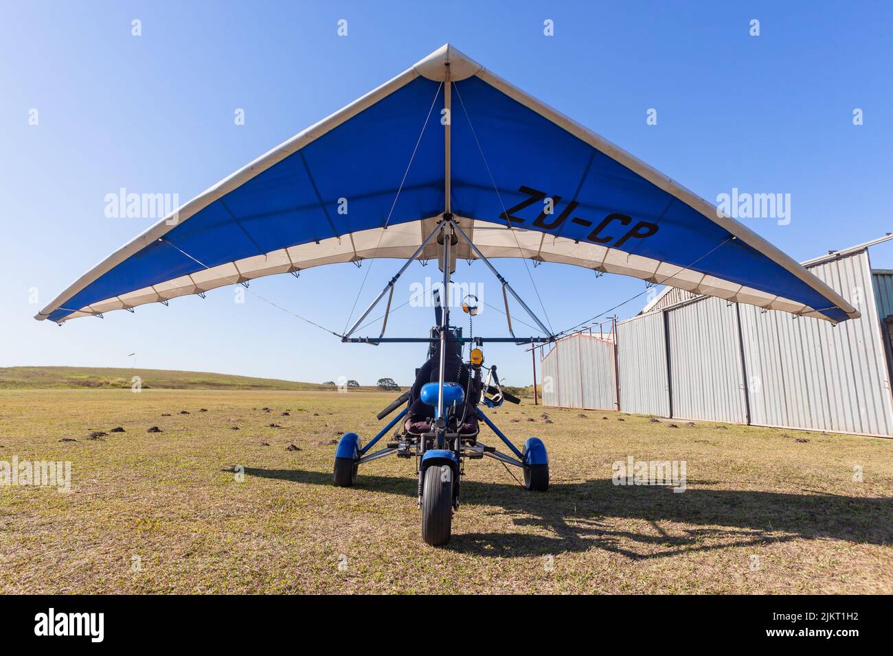 Flying microlight aircraft close up outside hangars on rural