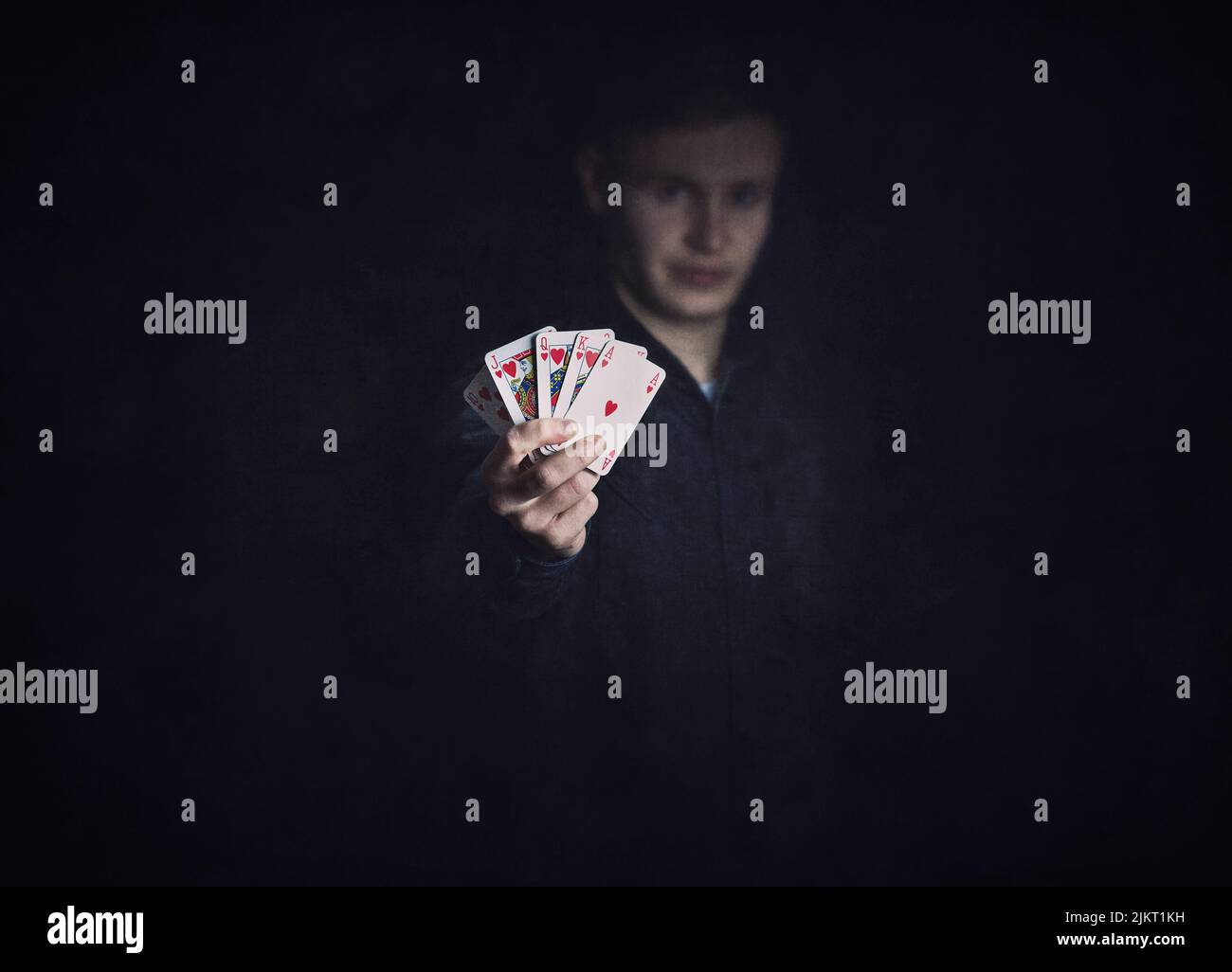Successful poker player holds up a winning royal flush combination. Lucky gambler with playing cards on a dark background. Casino tournament winner, v Stock Photo