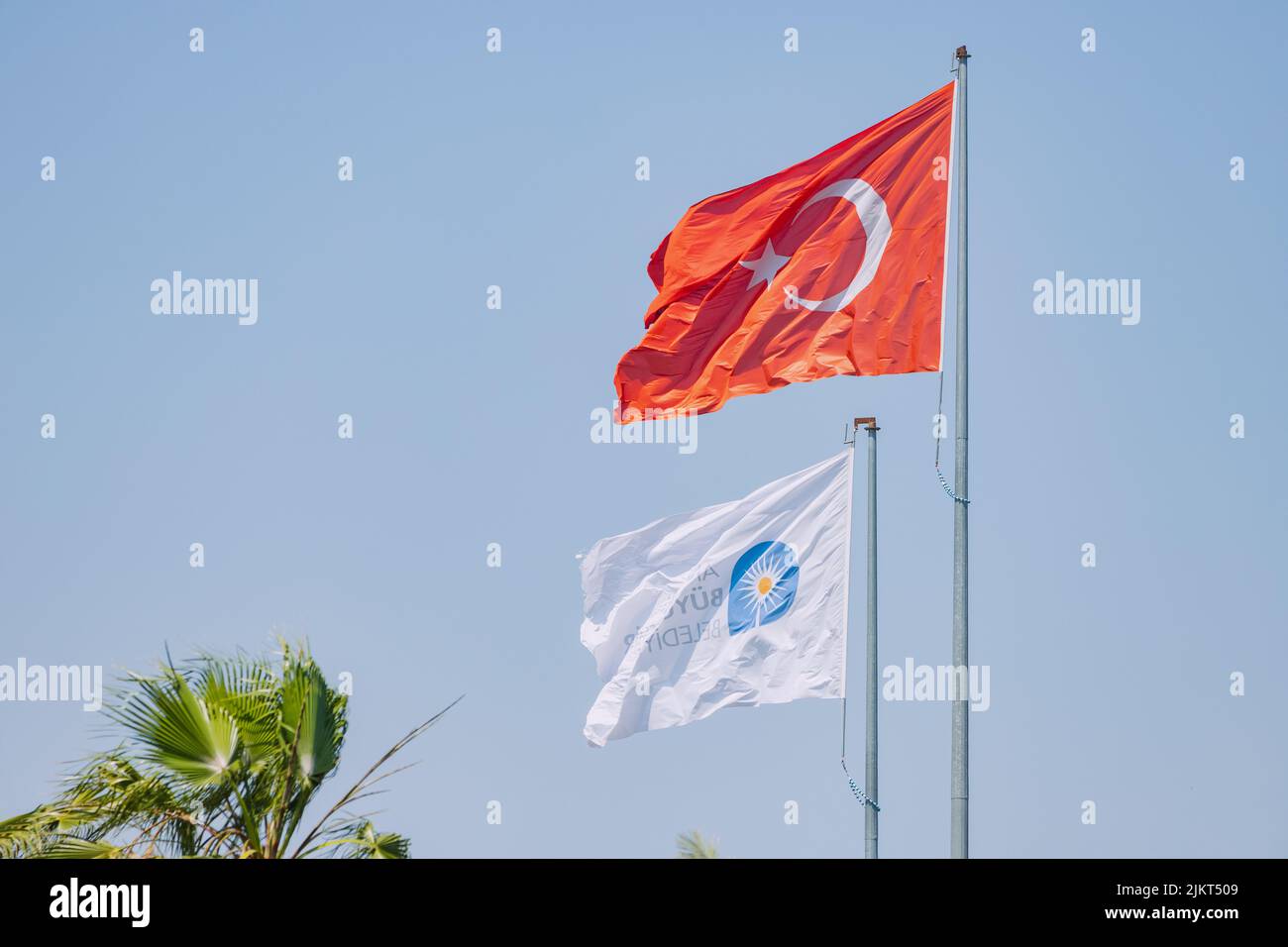 04 June 2022, Antalya, Turkey: Antalya minicipality and Turkish flag against blue sky Stock Photo