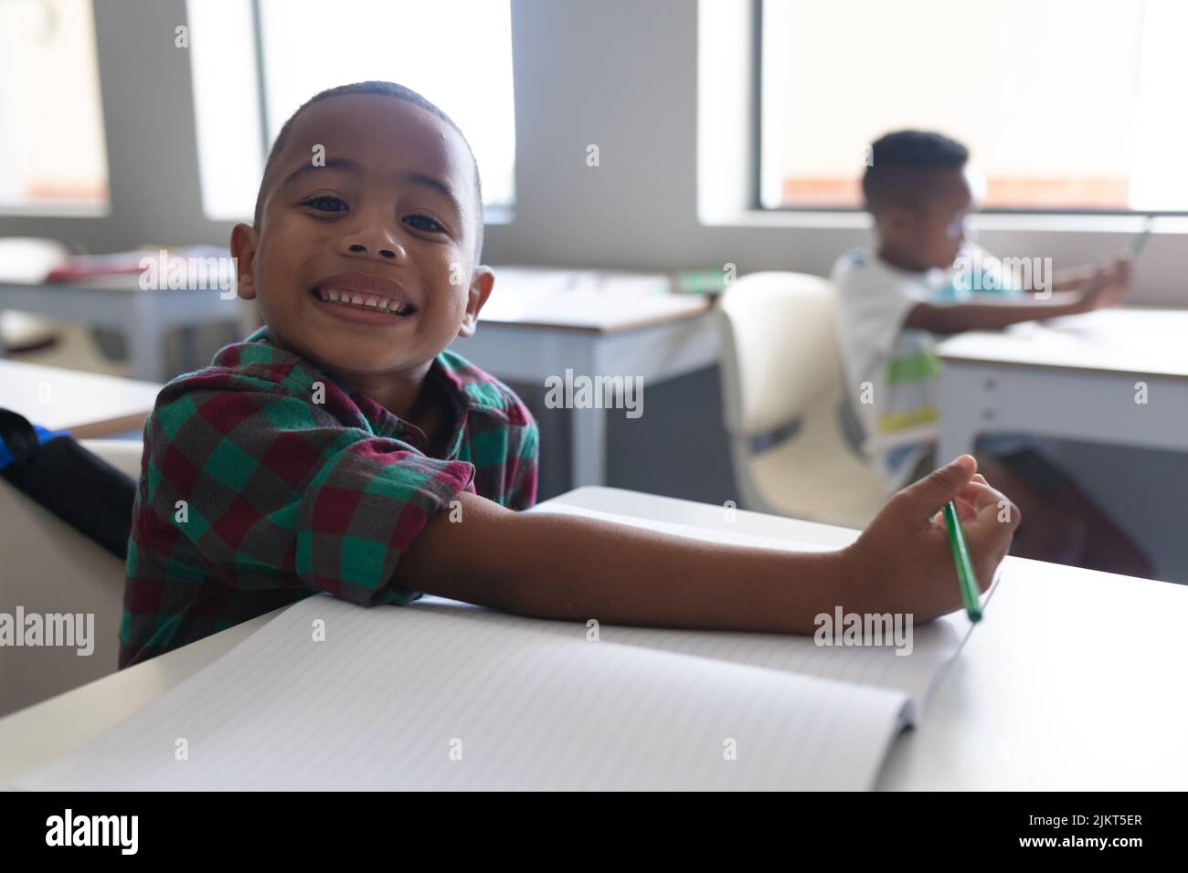 Portrait of smiling african american elementary schoolboy sitting at ...