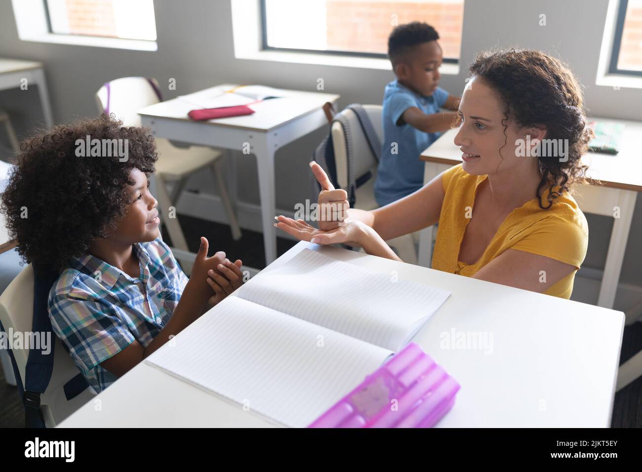 Caucasian young female teacher teaching sign language to african