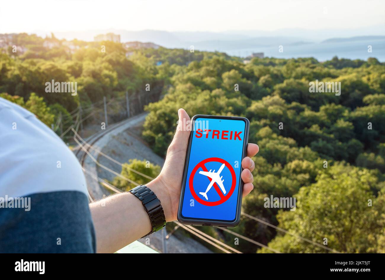 A Man Is Holding A Smartphone With A Notice On The Screen Strike, Flight Strike And Pilots Strike. Canceled Canceled Flight Icon Image PHOTOMONTAGE Stock Photo