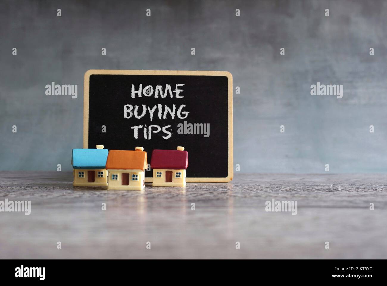 Toy houses and chalkboard with text HOME BUYING TIPS. Home ownership, real estate, property concept Stock Photo