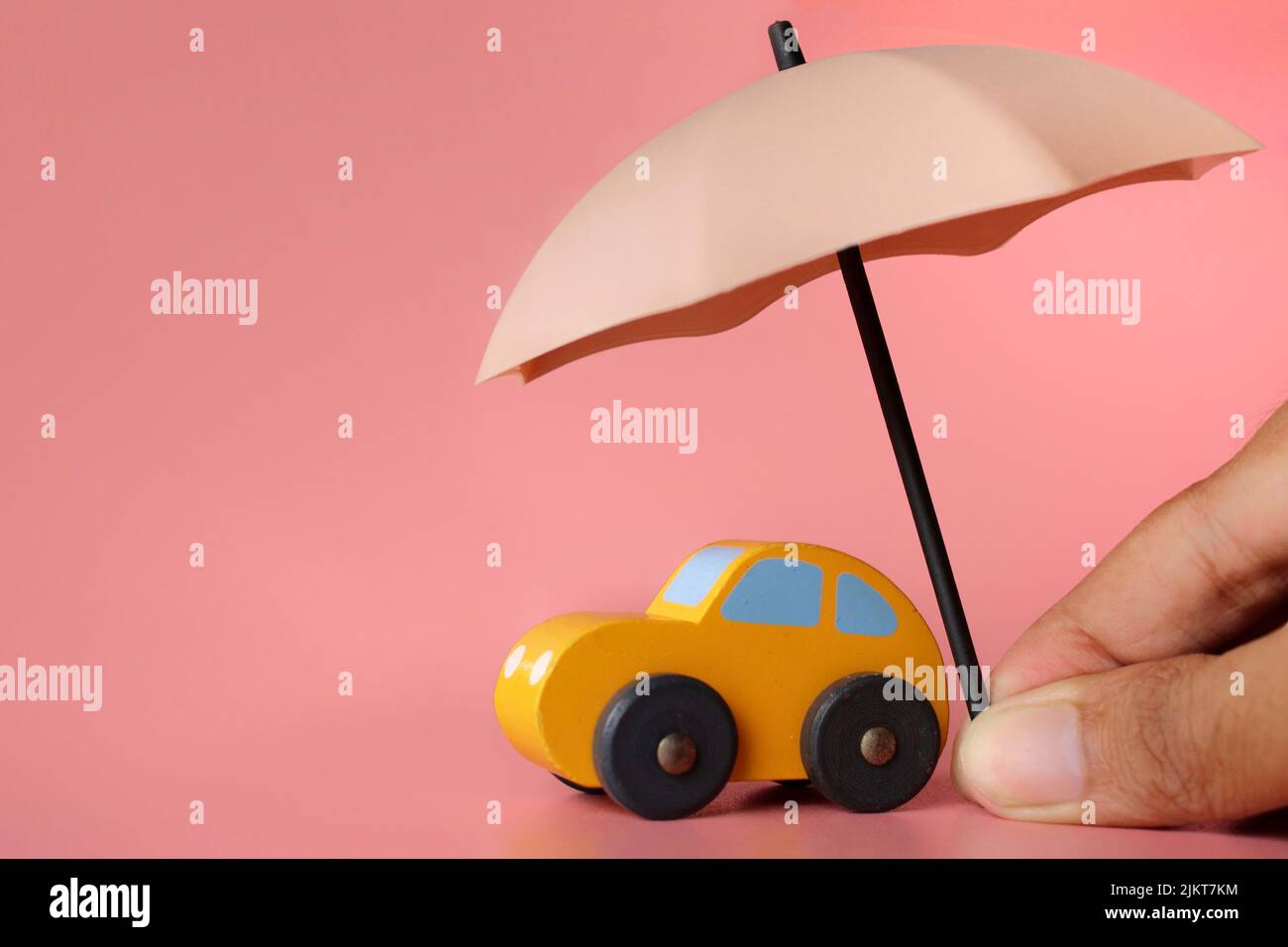 Umbrella and toy car with copy space. Car protection and insurance concept. Stock Photo