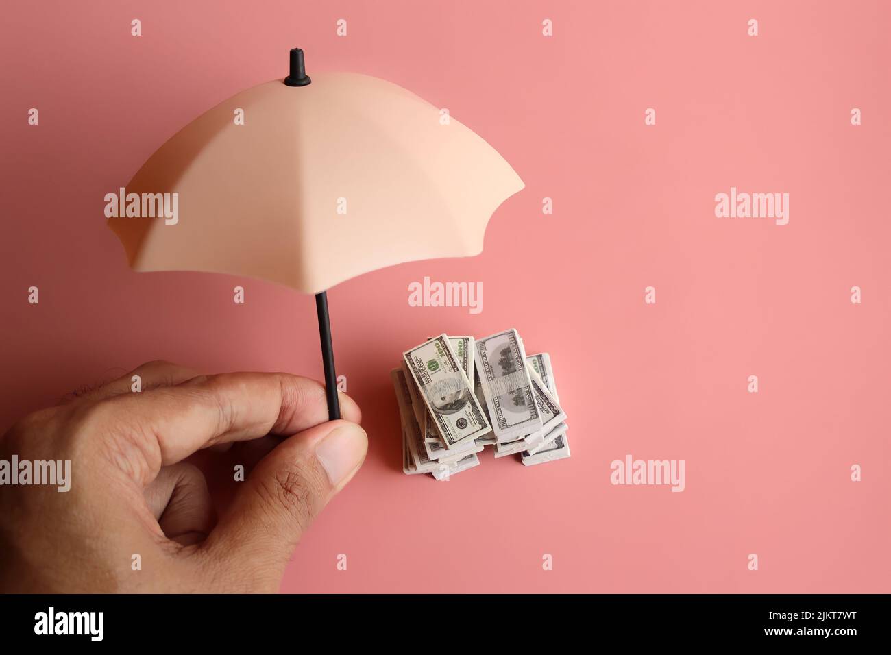 Stack of money and umbrella for protection with copy space. Financial safety and investment concept. Stock Photo